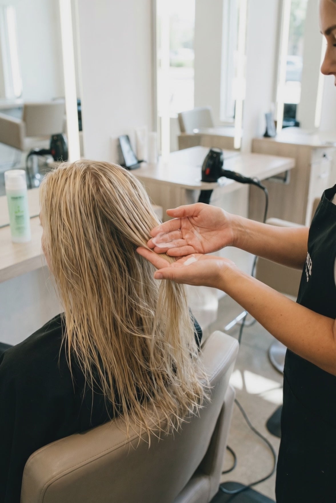 Stylist working product through hair at the salon chair